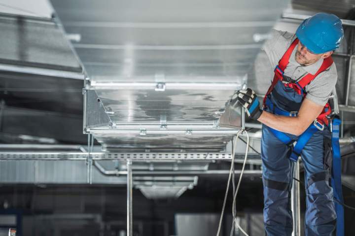 Technicien installant un conduit de fumée en inox, équipement de sécurité, chantier en cours.